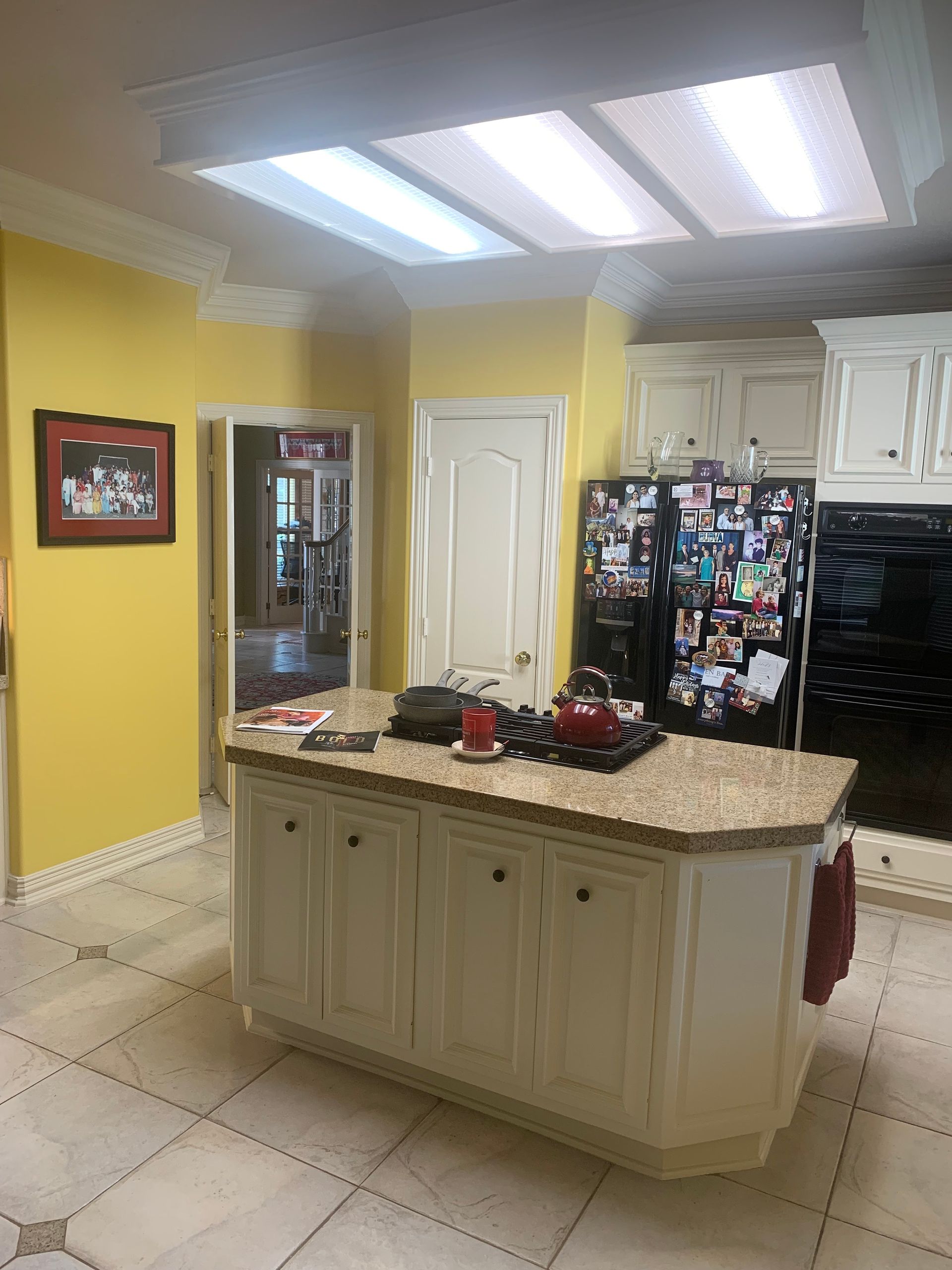 A kitchen with a large island , stove , refrigerator and oven.