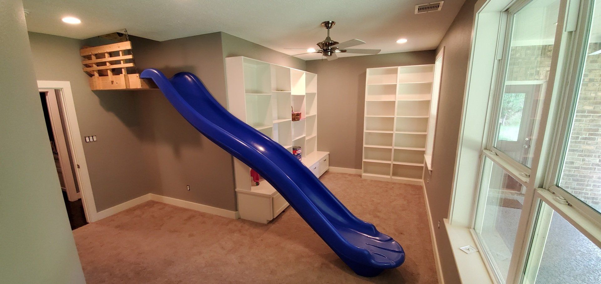 There is a blue slide in the middle of a room.