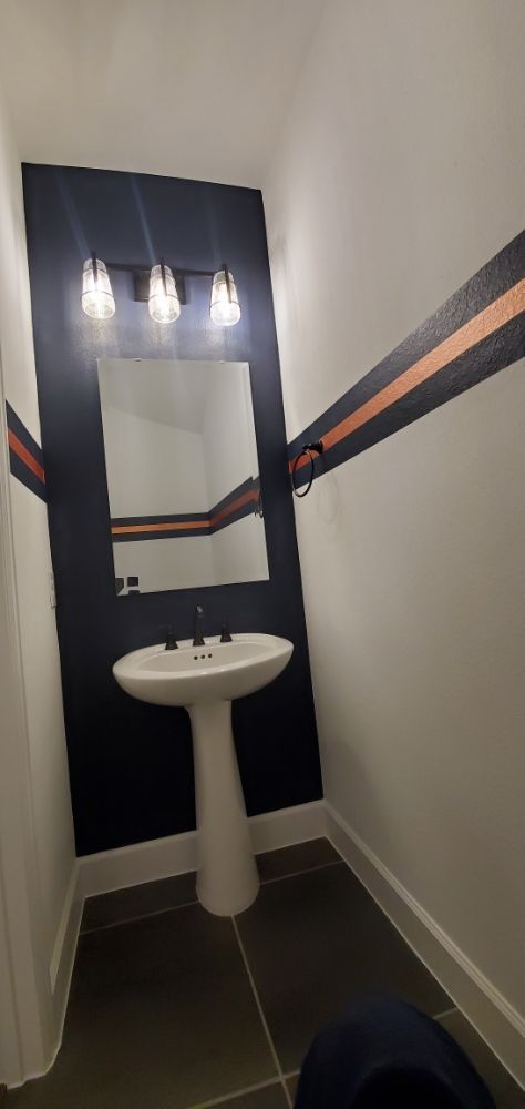 A bathroom with a sink , mirror , and striped walls.