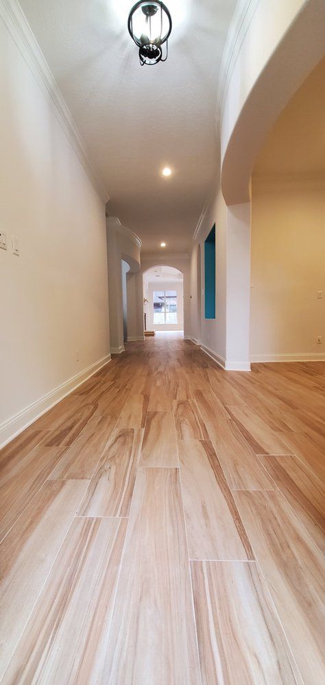 A long hallway with wooden floors and white walls in a house.