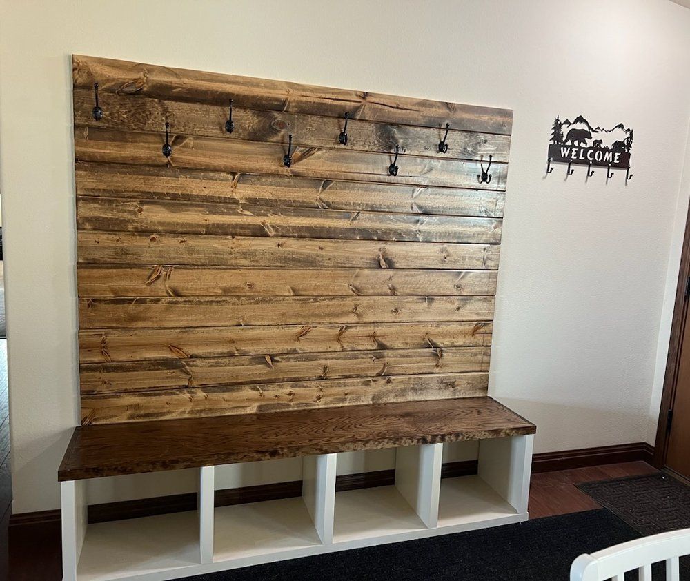 A wooden bench is sitting in front of a wooden wall with hooks.