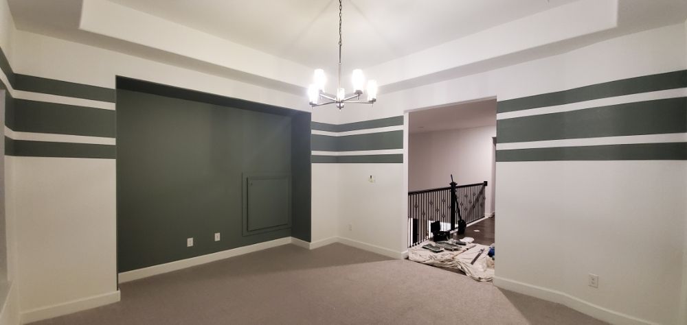 A dining room with green and white stripes on the walls and a chandelier.