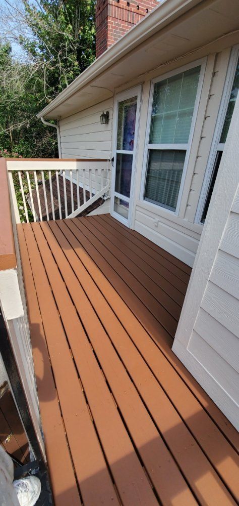 A wooden deck with a white railing on the side of a house.
