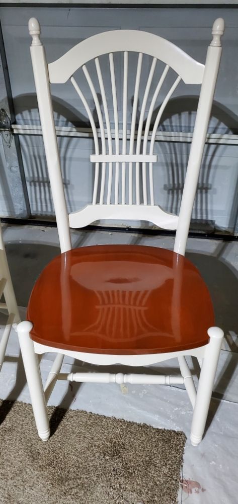 A white chair with a red seat is sitting on a carpet.