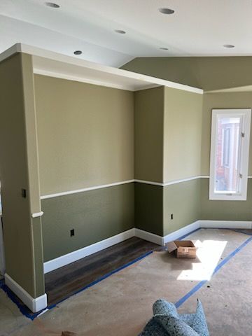 Interior room with olive and cream colored walls, white trim, and a window.