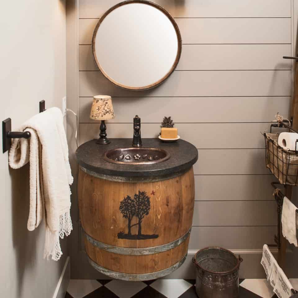 Rustic bathroom with a barrel vanity, round mirror, and gray shiplap walls.