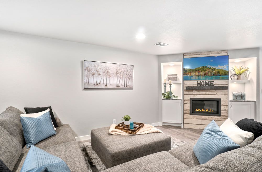 Cozy living room with gray sectional sofa, fireplace with TV, neutral colors, and decorative accents.
