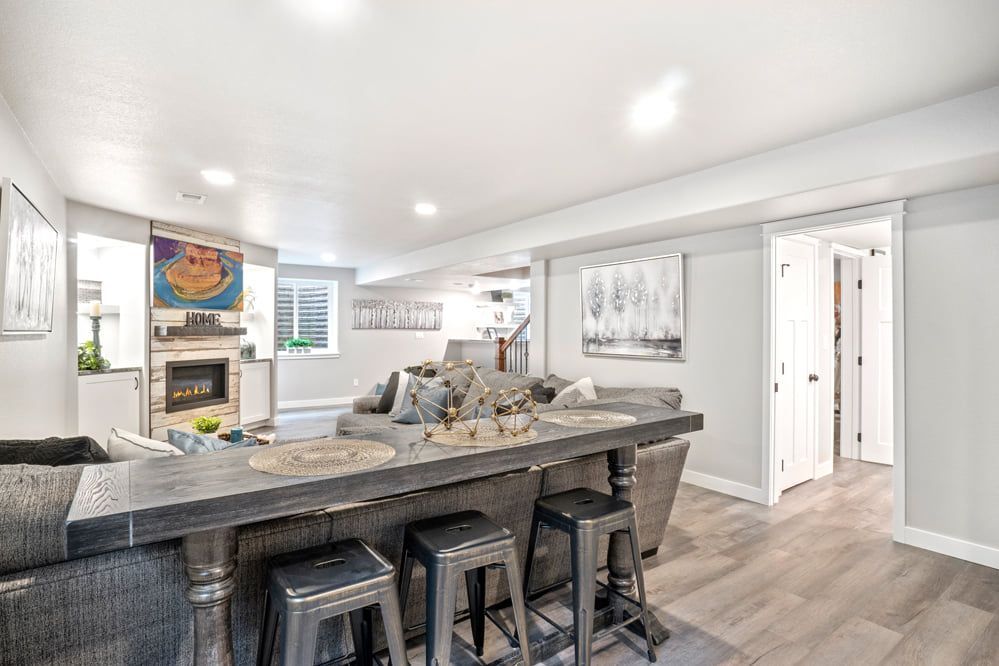A finished basement with a bar, fireplace, gray sofa, and light gray walls.