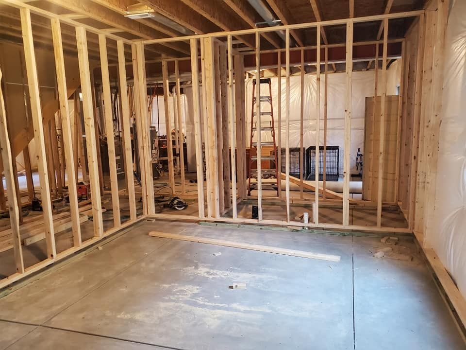Interior framing of a room under construction; wood studs, concrete floor.