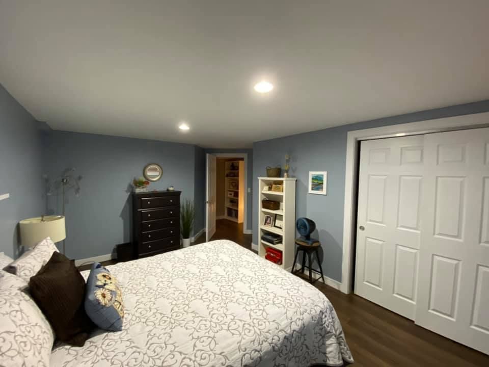 Bedroom with blue walls, white trim, bed, dresser, shelves, and closet.