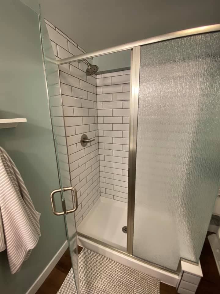Shower stall with white subway tile, glass doors, and silver fixtures.