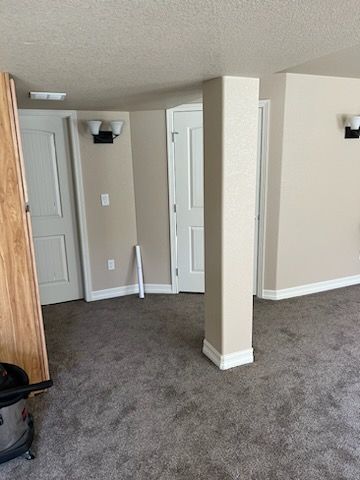 Interior room with carpet, doors, and a pillar; walls are beige.