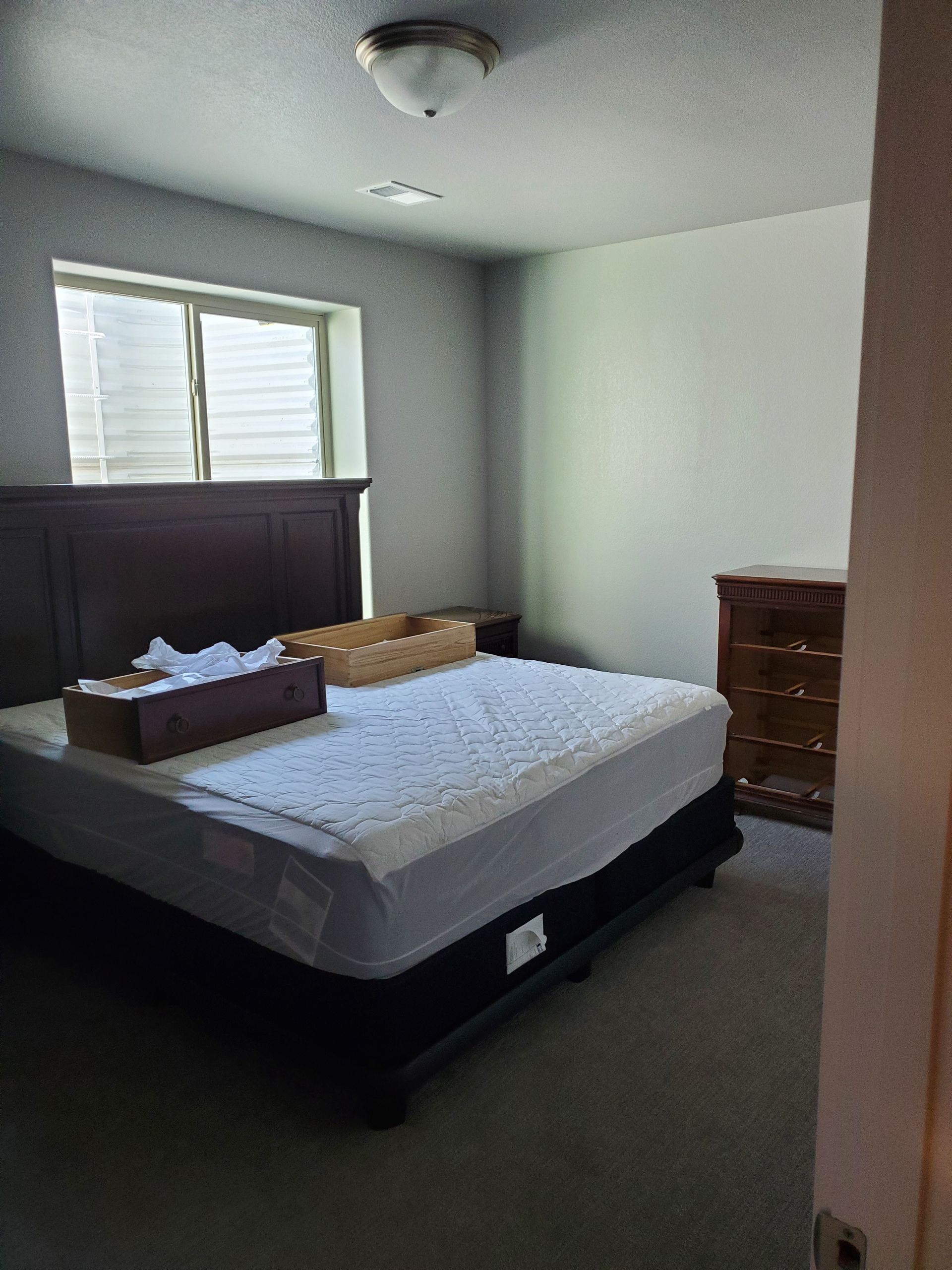 Bedroom with a bed, window, dresser, and light fixture.