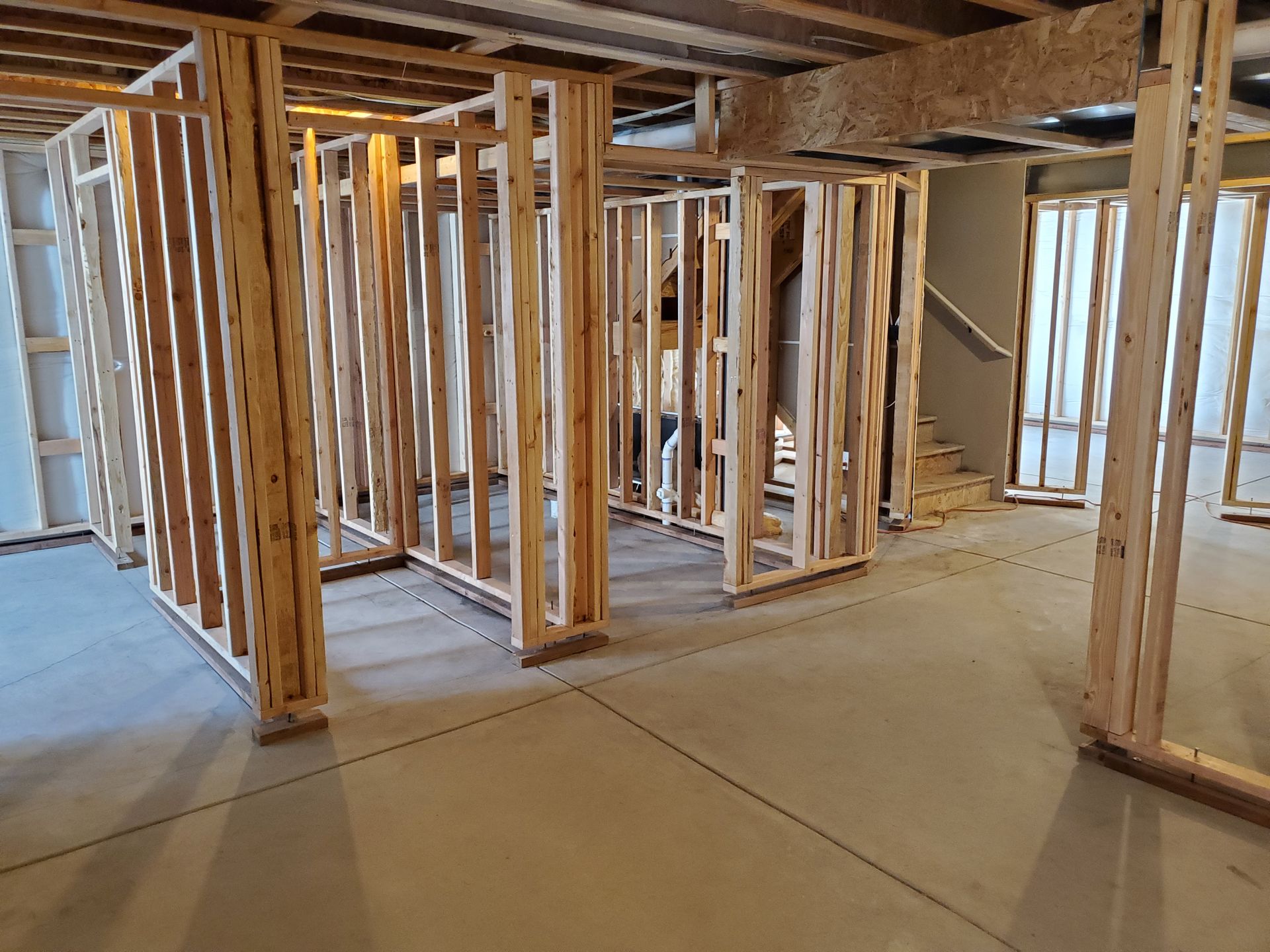 Basement under construction. Wooden frames define rooms on a concrete floor.