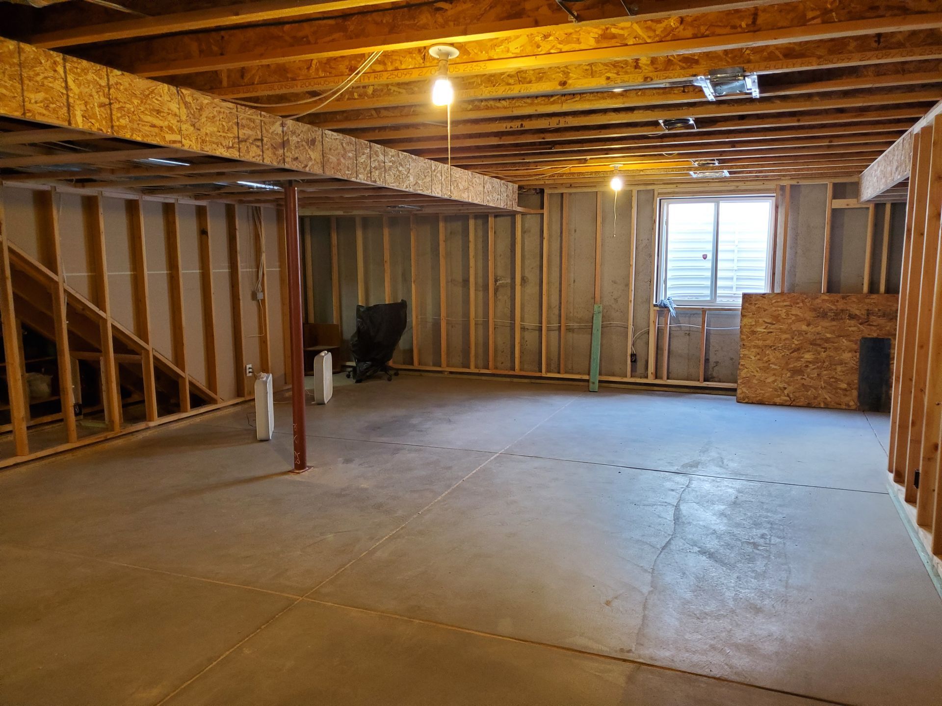 Unfinished basement with concrete floor, wood framing, and a small window.