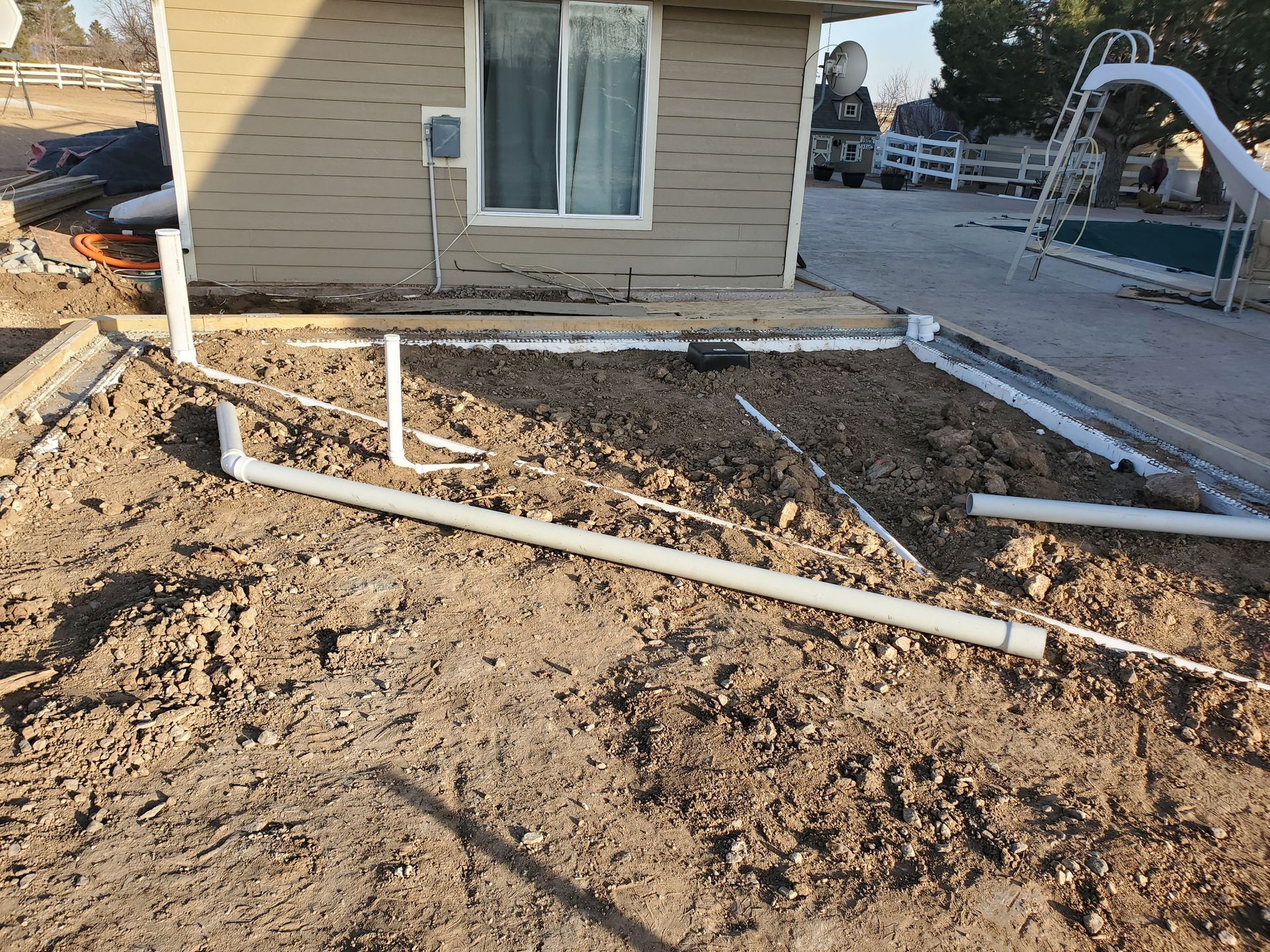 Construction site with exposed pipes, a building, and a playground.