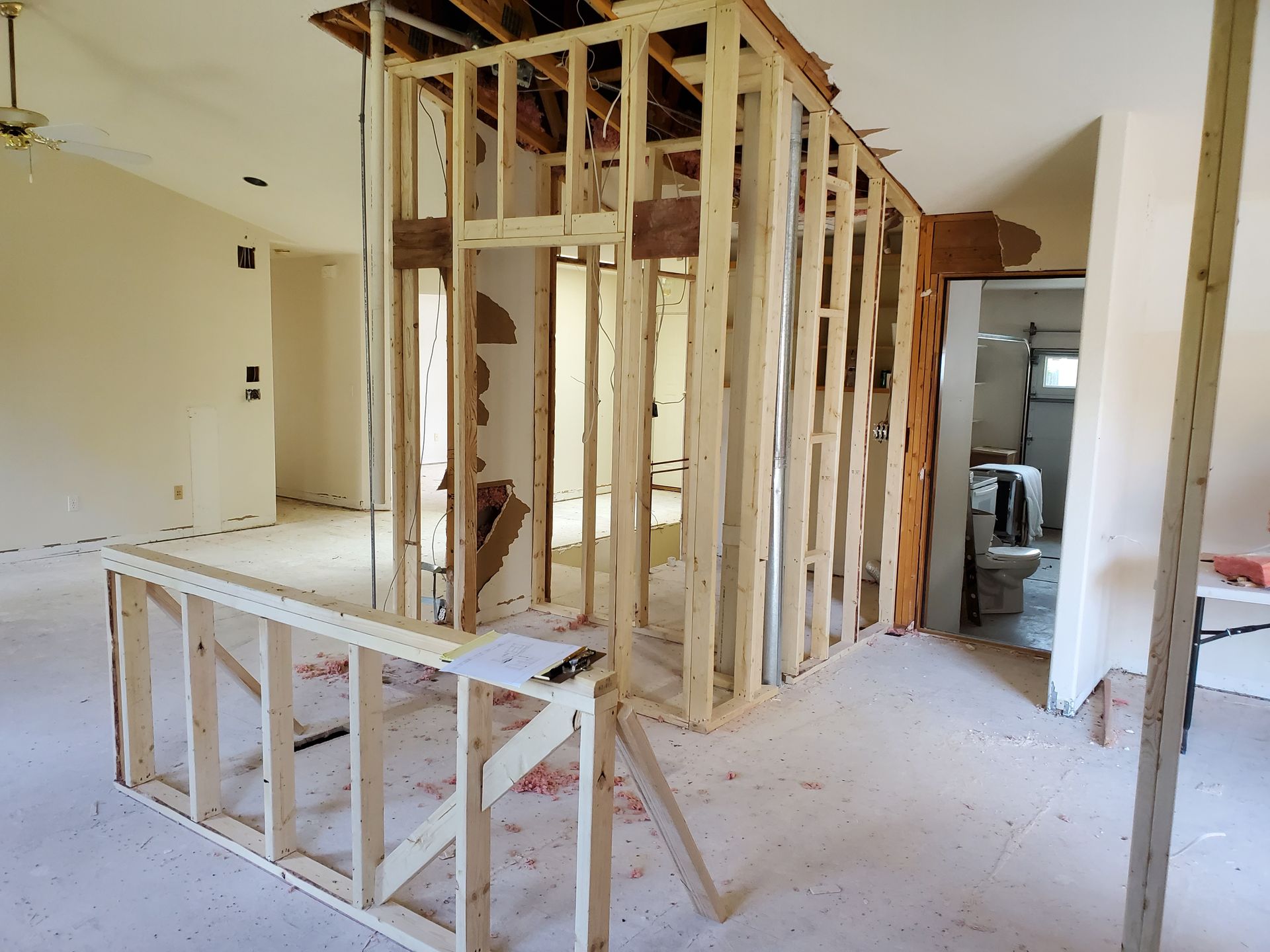 Interior with exposed wood framing, likely a renovation. Empty room, visible doorway to a bathroom.