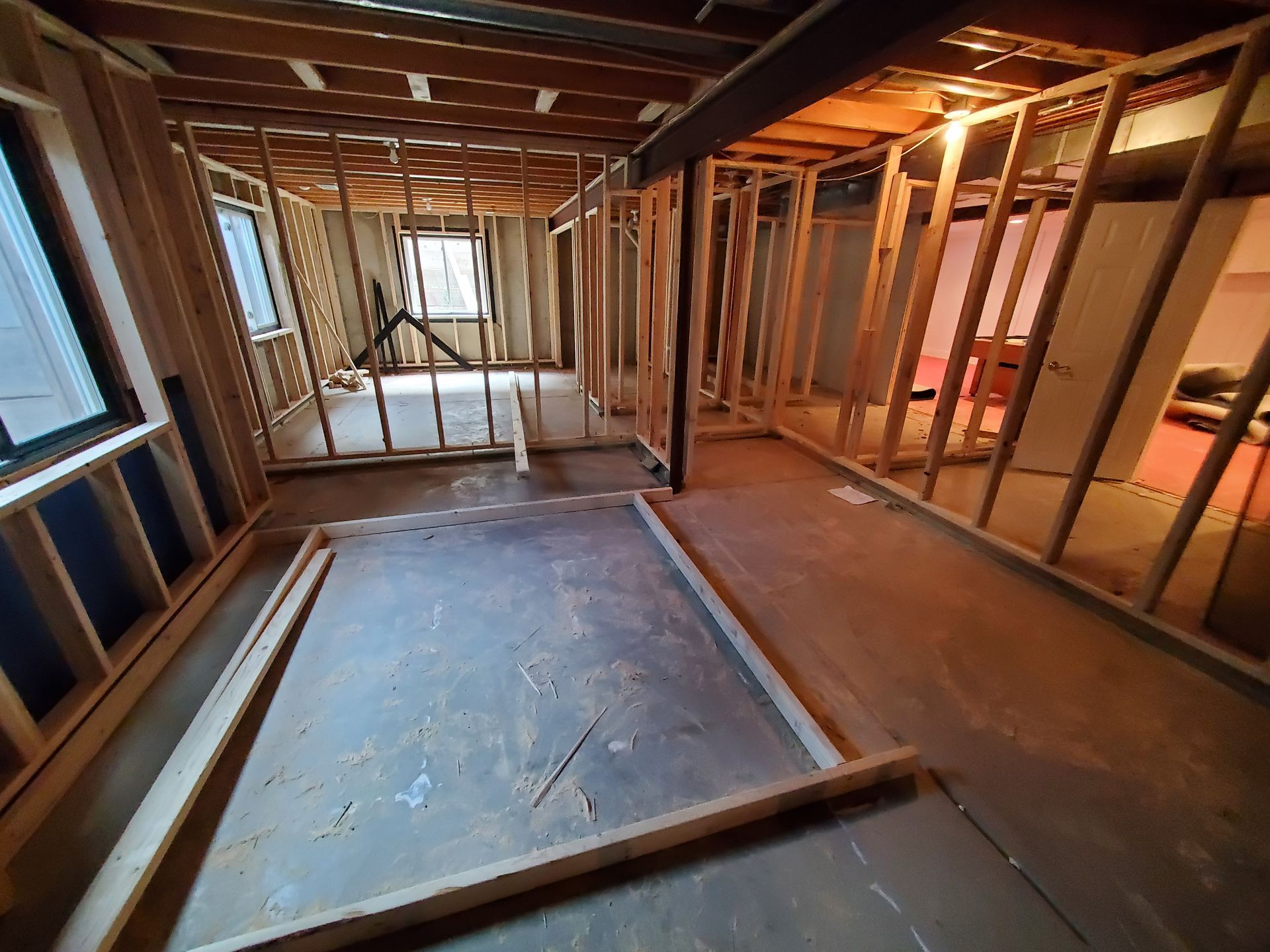 Interior view of a room under construction with wooden framing, unfinished walls, and exposed floor.