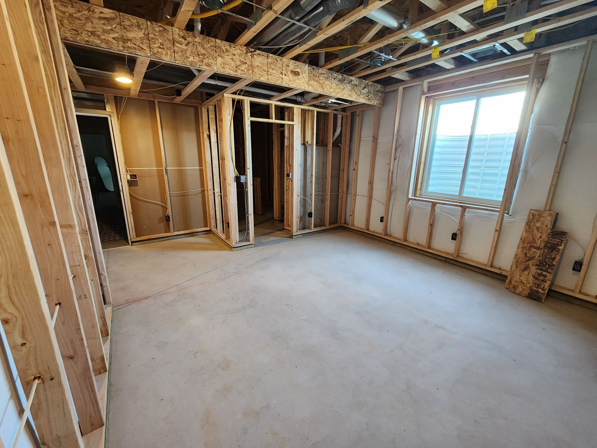 Unfinished basement room with wood framing and window. Ready for construction.