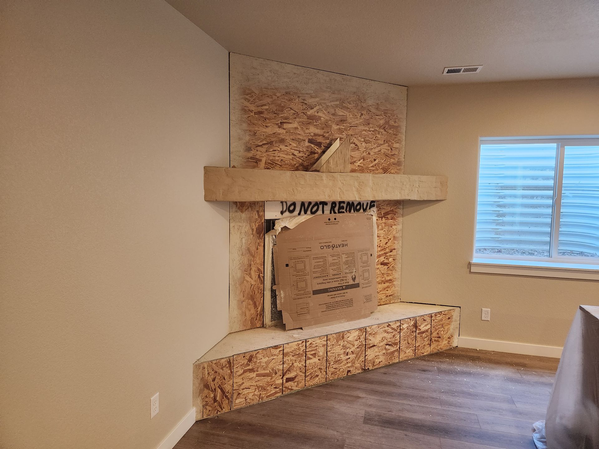 Unfinished fireplace in a room, constructed with OSB. 