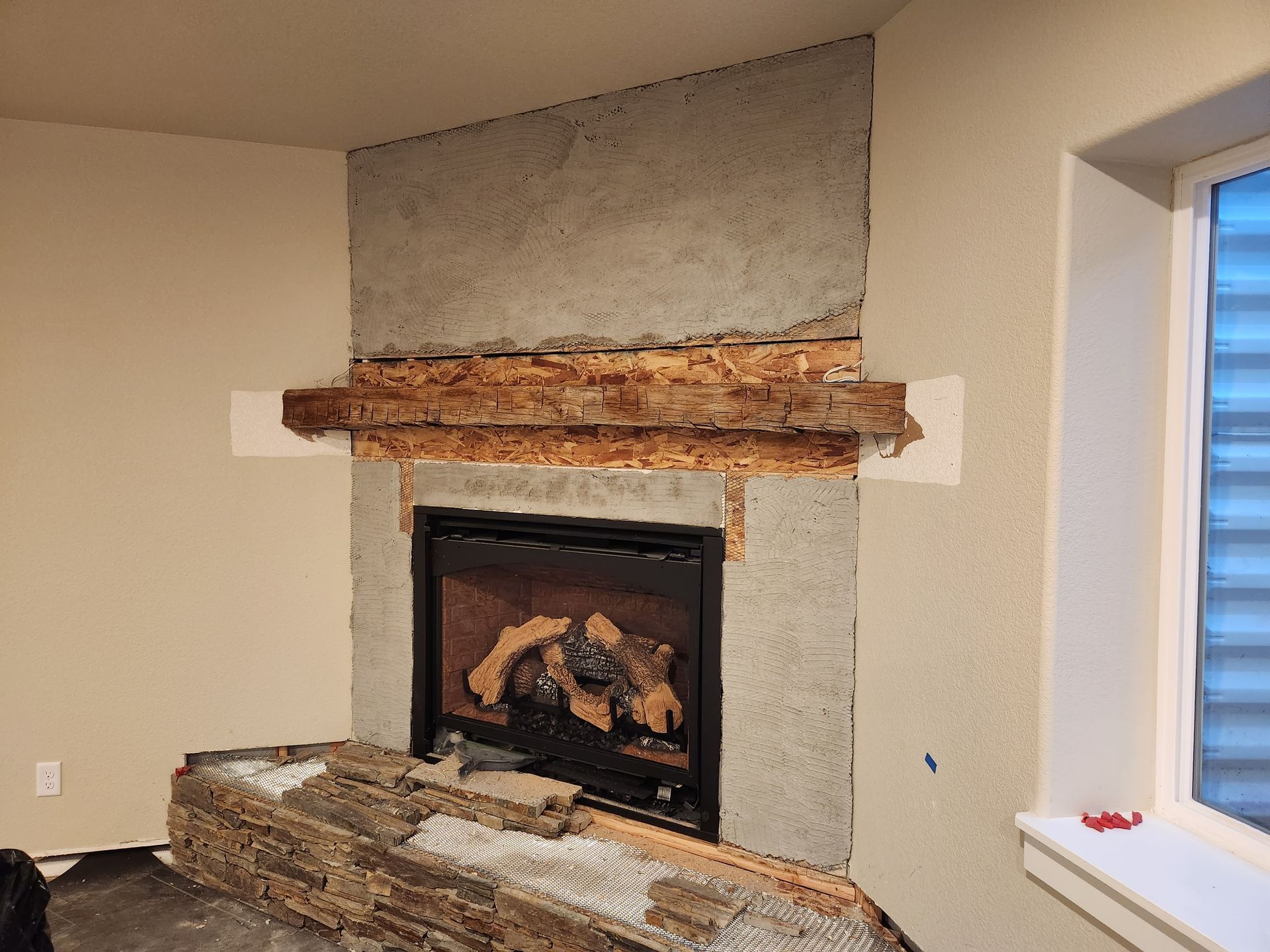 Fireplace under construction with stone veneer being installed.