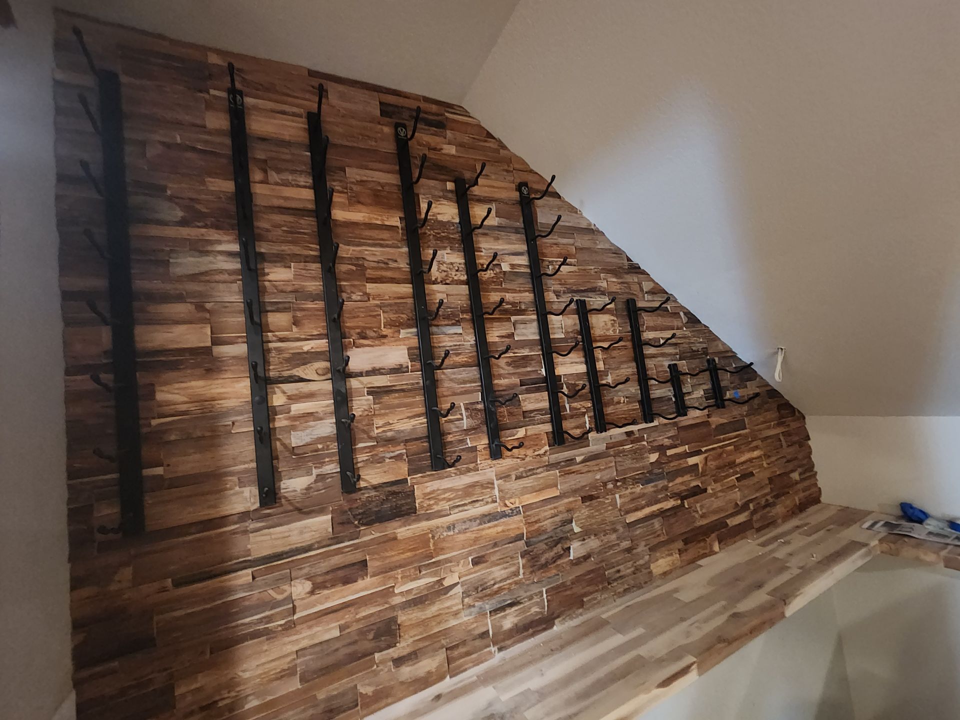 Wooden wall with wine bottle racks against a sloped ceiling.