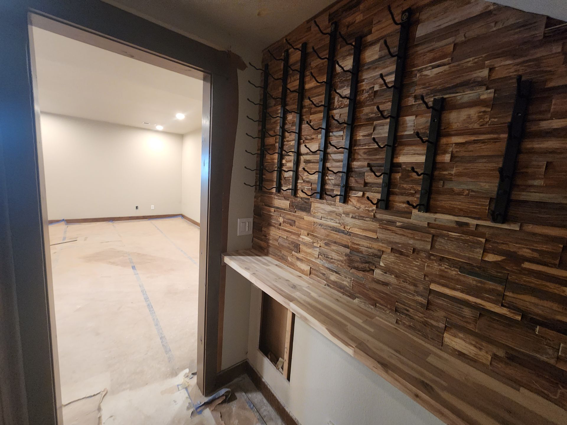 Hallway with wooden accent wall, coat racks, and doorway to an empty room.