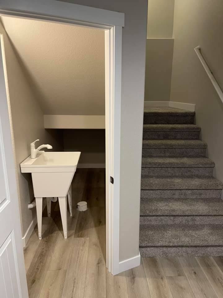 Laundry room with a sink and a staircase with gray carpet.