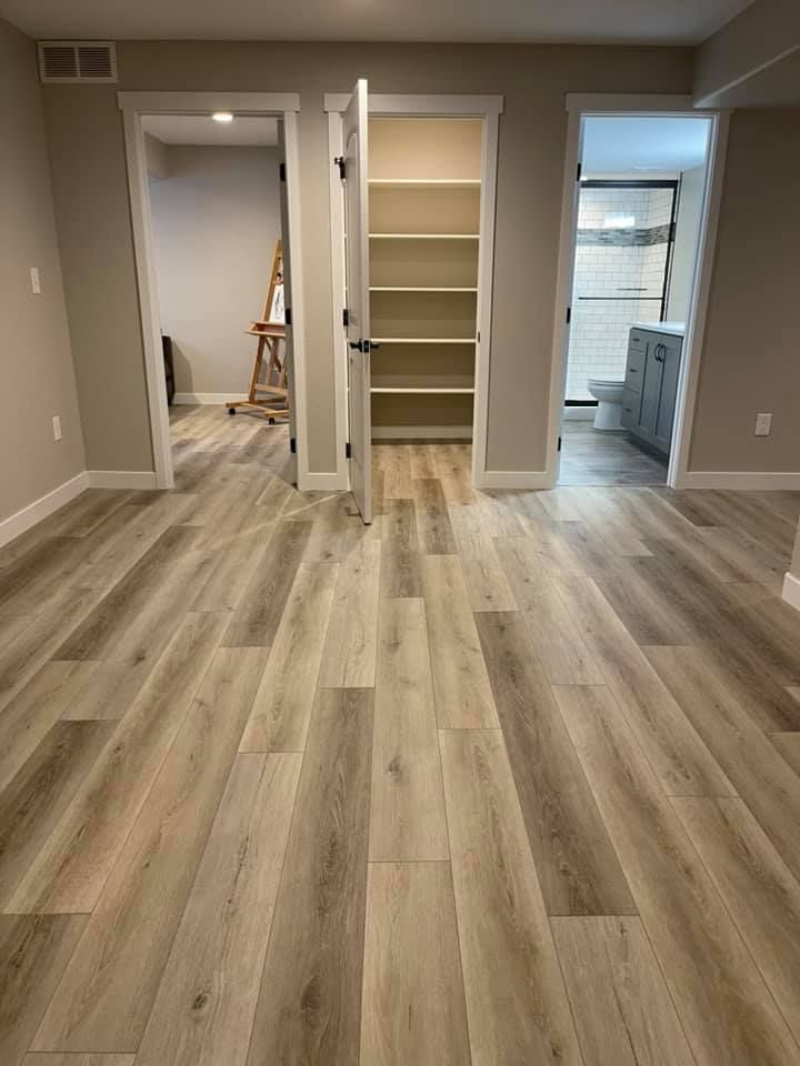 Interior view of a room with light wood-look flooring. Open doors lead to a bathroom, closet, and another room.