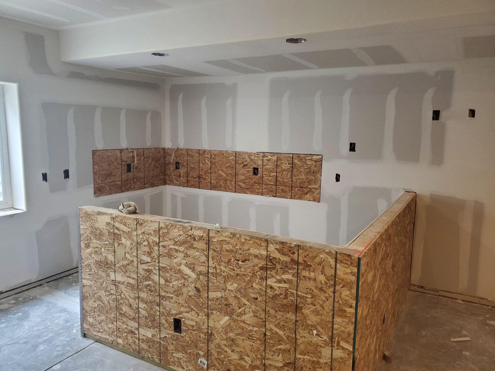 Interior construction: room with drywall, a plywood bar structure, and recessed lighting.