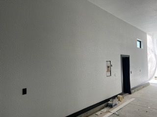 Gray painted interior wall with a black door, a small window, and electrical fixtures.