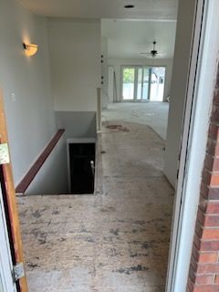 Entryway: Open doorway reveals a hallway with a staircase to the left and a living area.