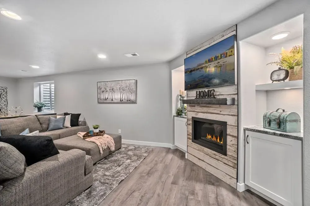 Living room with gray sectional sofa, fireplace with TV, and built-in shelves.