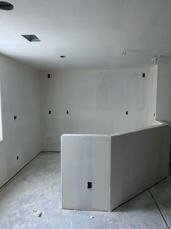Interior view of a room under construction, with white walls, a curved half-wall, and electrical outlets.