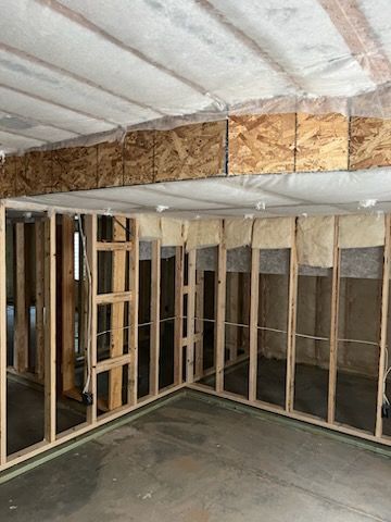 Unfinished room with wood framing, insulation, and concrete floor.