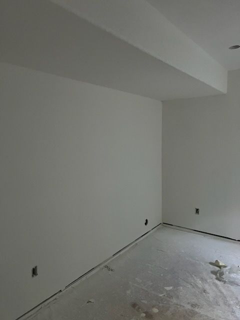 Empty room with white walls, concrete floor, and a ceiling beam.