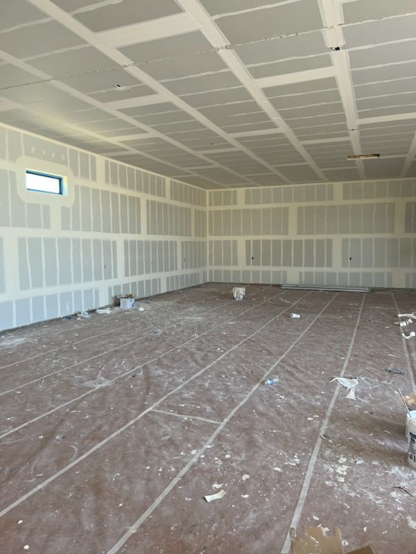 Unfinished room with drywall walls and ceiling, floor covered in protective paper.