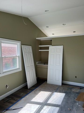 Room under construction with two white doors, green walls, and a built-in cabinet.