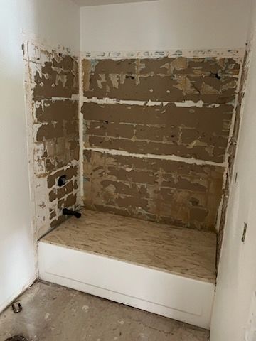 Bathroom with exposed wall studs, bathtub base, and white walls.
