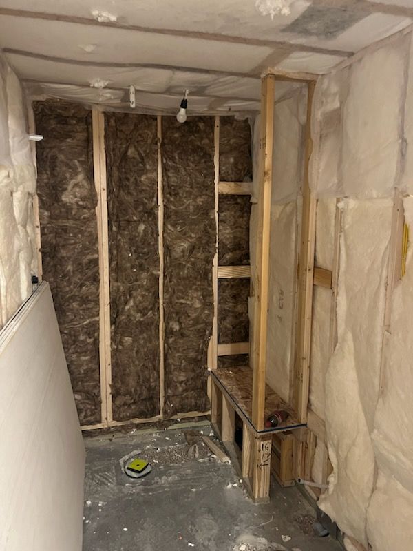 Interior view of a room under construction, with insulation and wooden framing visible; a small ledge is built-in.