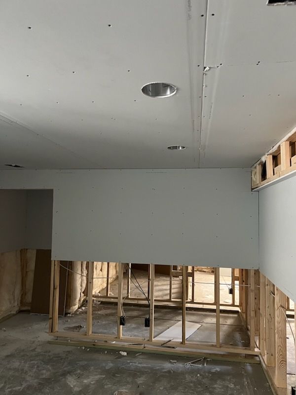 Interior view of a room under construction, featuring exposed wooden framing and drywall.