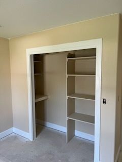 Empty closet with shelves on the right side and a small shelf on the left. Tan walls and white trim.