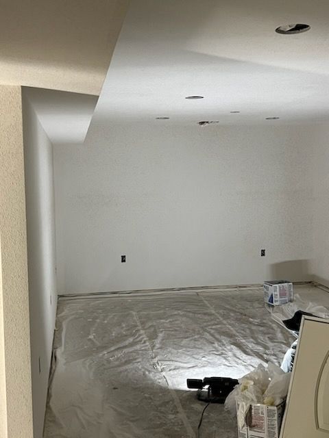 Newly painted white room, drop ceiling, plastic floor covering. Power outlets and recessed lights visible.
