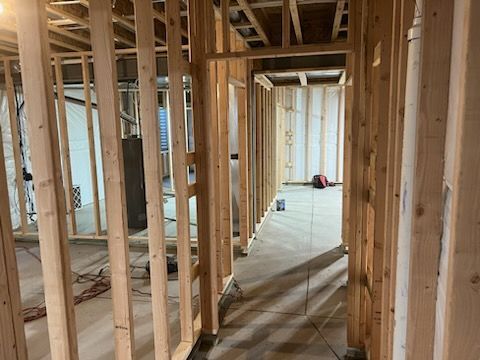 Interior view of a building under construction. Wooden framing defines walls and doorways.