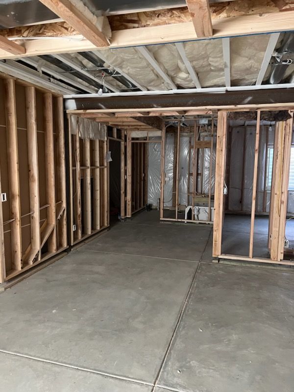Basement renovation in progress. Concrete floor, wooden studs, exposed ceiling, and framing define the interior space.
