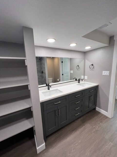 Gray bathroom with a double vanity, large mirror, and shelving.