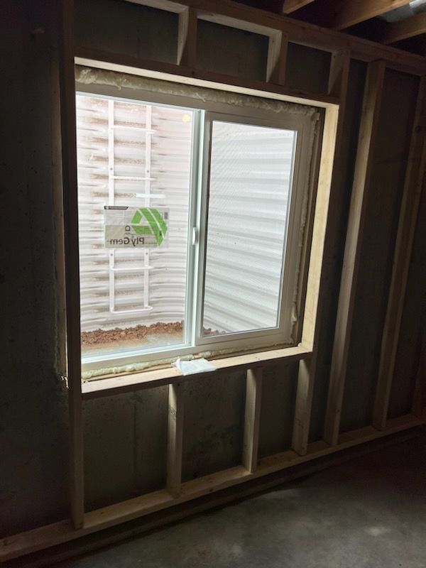 Framed window in unfinished basement, white frame, open and closed window, and an empty window well.