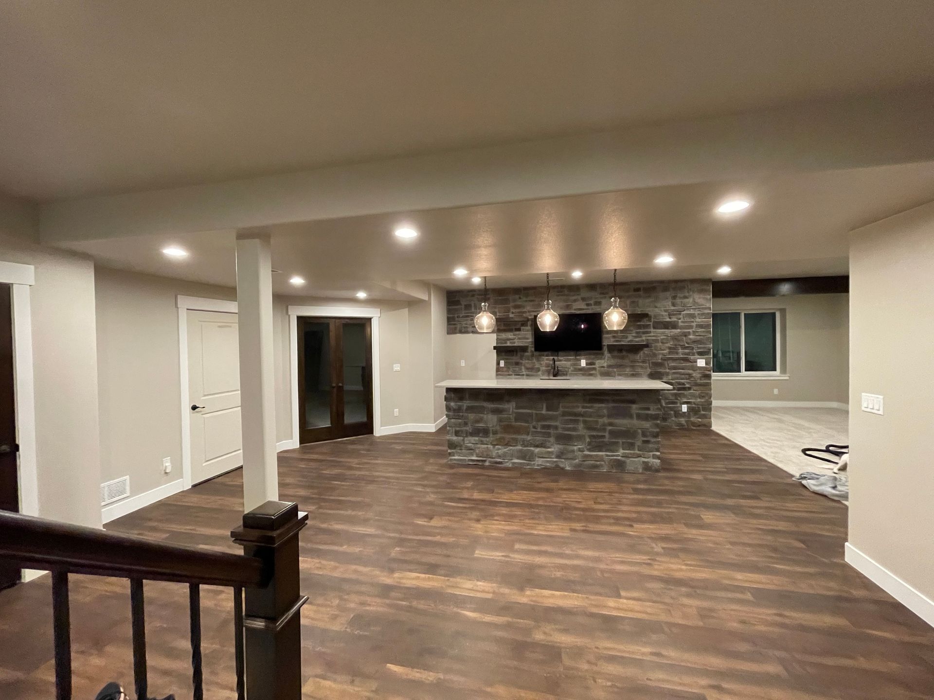 Finished basement with a bar, dark wood flooring, and stone accent wall.