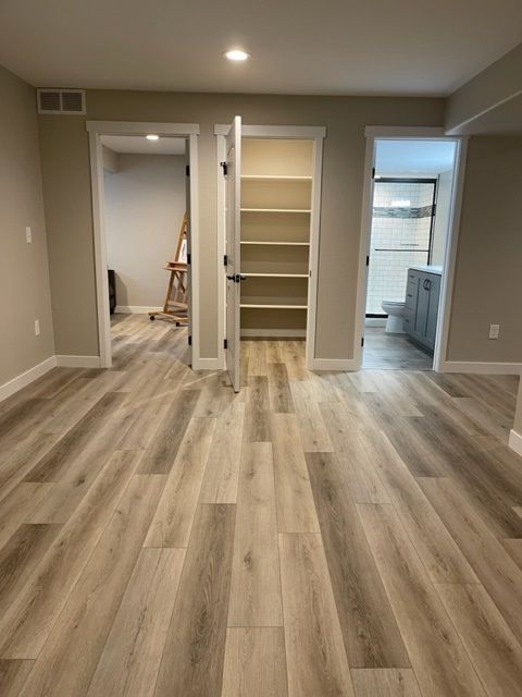 Interior view with wood-look floor, doorways to a bathroom, pantry, and room with easel.