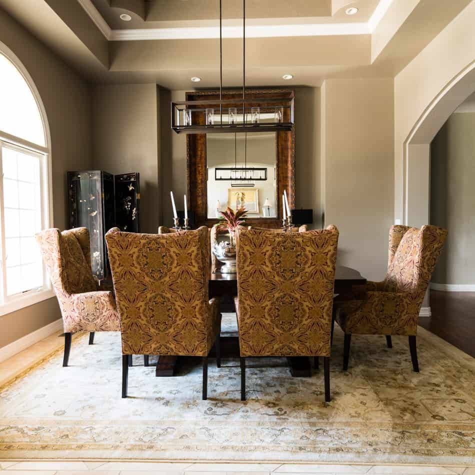 Dining room with patterned chairs, dark table, and large mirror.